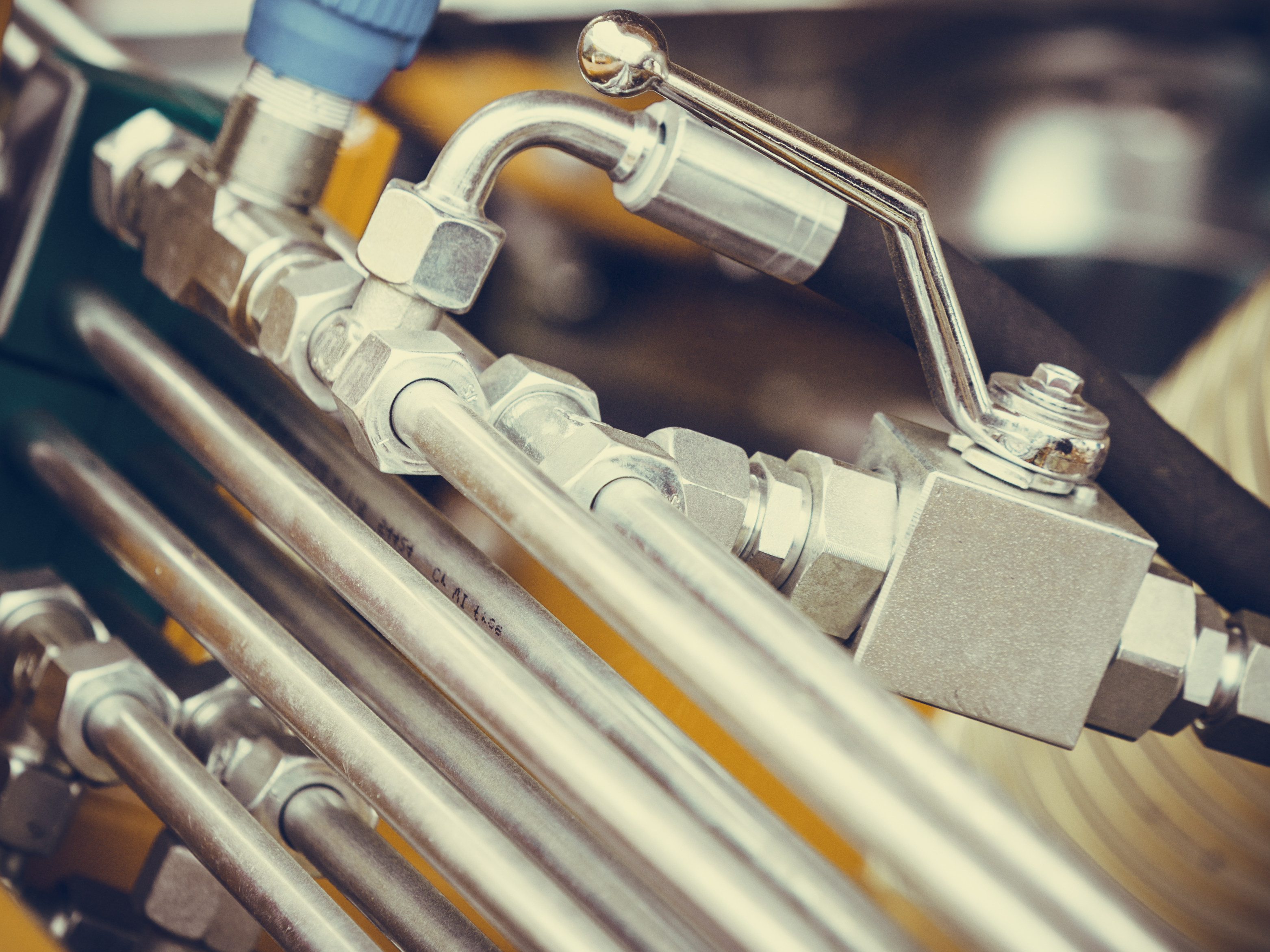 Close-up of rigid hydraulic tubing connected to fittings and a valve